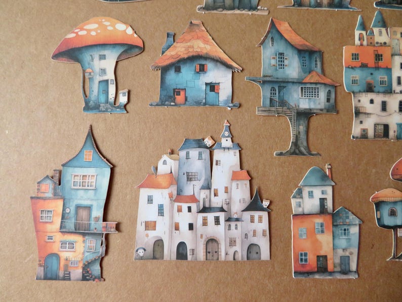 May include: A collection of whimsical paper cutouts of colorful houses and a mushroom-shaped structure. The houses feature various architectural styles with orange, blue, and white color schemes. The cutouts are arranged on a brown background.