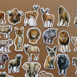 May include: A selection of animal stickers with watercolour illustrations of African wildlife. The stickers include a leopard, buffalo, deer, lion, hippo, zebra, and more. The stickers are on a brown background.