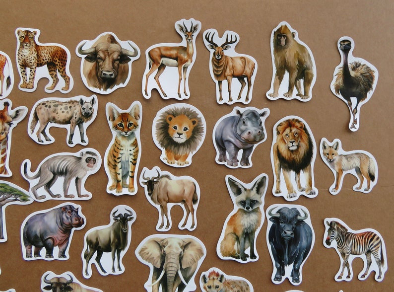 May include: A selection of animal stickers with watercolour illustrations of African wildlife. The stickers include a leopard, buffalo, deer, lion, hippo, zebra, and more. The stickers are on a brown background.