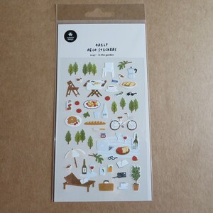 K&ouml;nnte beinhalten: Eine Packung dekorativer Aufkleber mit Gartenthema. Die Aufkleber zeigen Illustrationen von B&auml;umen, Essen, einem Fahrrad und Gartenm&ouml;beln. Der Text "DAILY DECO STICKERS" und "1147 in the garden" sind auf der Verpackung aufgedruckt.
