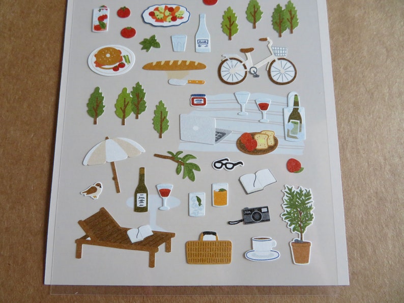 K&ouml;nnte beinhalten: Ein Stickerbogen mit Illustrationen von Picknick- und Freizeitartikeln. Enth&auml;lt ein Fahrrad, Weinflaschen, Essen, B&auml;ume, eine Sonnenliege und eine Kamera. Die Aufkleber sind im Cartoon-Stil mit neutraler Farbpalette.