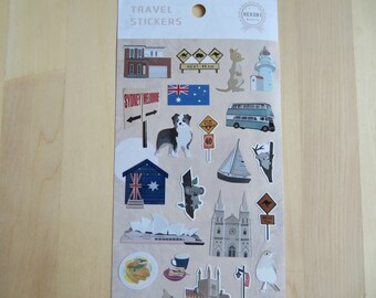 May include: A sheet of travel stickers featuring Australian landmarks and icons. The stickers include a kangaroo, a lighthouse, a double-decker bus, a sailboat, a koala, and the Sydney Opera House. The text "TRAVEL STICKERS" is at the top.