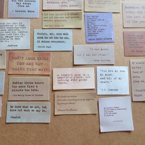 May include: A collection of rectangular paper cards with quotes printed in various fonts. The cards are in shades of beige, brown, and cream, with text in black. Quotes include lines from Shakespeare, Keats, and Austen. The cards are arranged on a neutral surface.