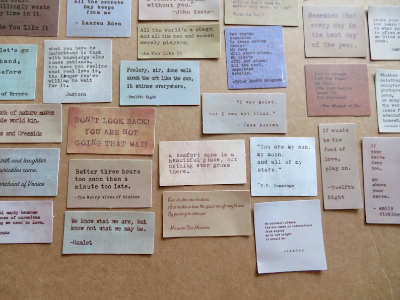 May include: A collection of rectangular paper cards with quotes printed in various fonts. The cards are in shades of beige, brown, and cream, with text in black. Quotes include lines from Shakespeare, Keats, and Austen. The cards are arranged on a neutral surface.