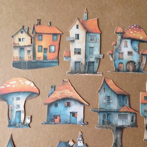 May include: A collection of whimsical paper cutouts of houses and mushroom-shaped dwellings. The houses feature orange, blue, and beige color schemes with detailed architectural elements. The mushroom houses have orange and white spotted caps.