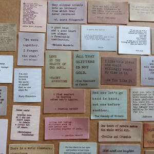 May include: A collection of small, rectangular cards with quotes printed in black ink. The cards are in various colors, including beige, pink, and green. The quotes are from famous authors and philosophers.