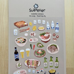 May include: A sheet of Suatelier stickers with illustrations of food items. The stickers depict dishes such as grilled fish, soup, sushi, beer, and water bottles. The text "Suatelier stickers" and "food trip #3" are displayed on the sheet.