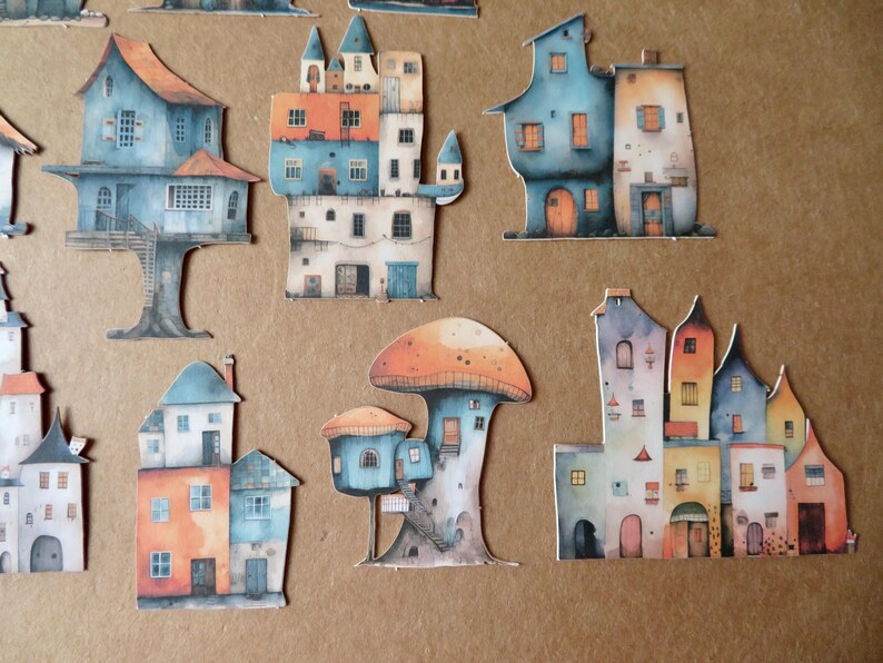 May include: A collection of whimsical, watercolor-style paper cutouts of colorful houses and mushroom-shaped structures. The houses feature various architectural styles and are painted in shades of blue, orange, and white. The overall theme is fantasy and fairytale.
