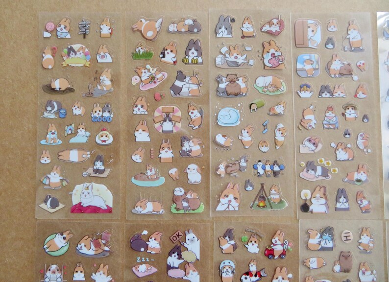May include: Sheets of stickers featuring various cartoon rabbits in different poses and settings. The stickers include rabbits with orange, white, and gray fur, some with accessories. The word "GOOD" is visible on one sticker.