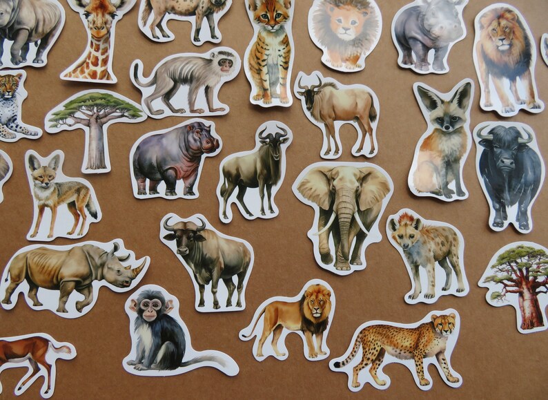 May include: A selection of animal stickers with watercolour illustrations of African wildlife. Includes a giraffe, lion, elephant, rhino, cheetah, and more. The stickers are on a brown background.