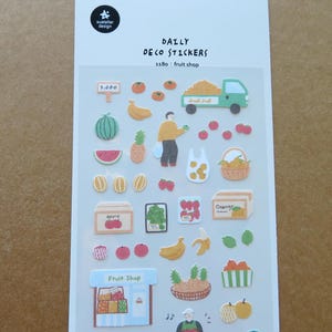May include: Sheet of Daily Deco Stickers featuring fruit shop themed illustrations. Includes stickers of various fruits like watermelon, bananas, and oranges, along with a fruit truck and a fruit shop sign. The stickers are colorful and cartoon-like.
