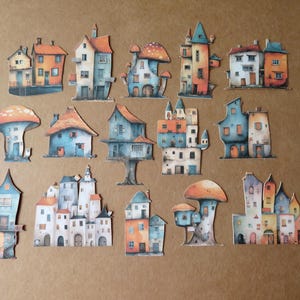 May include: A collection of whimsical, colorful paper cutouts of houses and mushroom-shaped dwellings. The houses feature orange, blue, and white facades with various architectural styles. The cutouts are arranged on a brown surface.