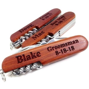 May include: Four wooden pocket knives with personalized engravings. The knives have a corkscrew, bottle opener, and other tools. The engravings include "Doug Groom 9-30-17", "Mac Best Man 9-30-17", "Blake", and "Groomsman 8-18-18".