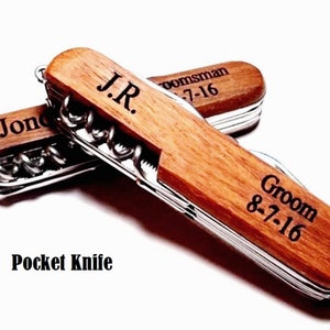 May include: Two wooden pocket knives with personalized engravings. The top knife has the text "J.R. groomsman 8-7-16" and the bottom knife has the text "Groom 8-7-16".