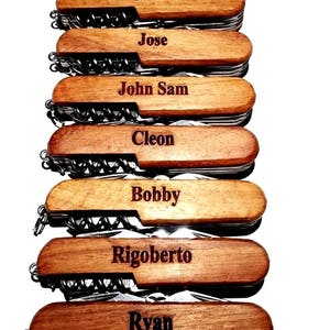 May include: Eight personalized wooden handled pocket knives with different names engraved on each handle. The names are Daniel Lee, Juan, Jose, John Sam, Cleon, Bobby, Rigoberto, and Ryan.