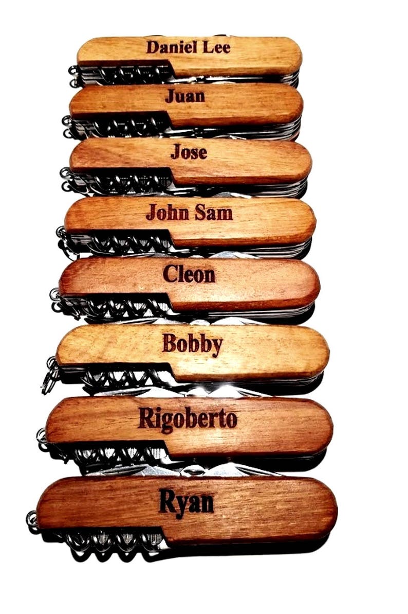 May include: Eight personalized wooden handled pocket knives with different names engraved on each handle. The names are Daniel Lee, Juan, Jose, John Sam, Cleon, Bobby, Rigoberto, and Ryan.
