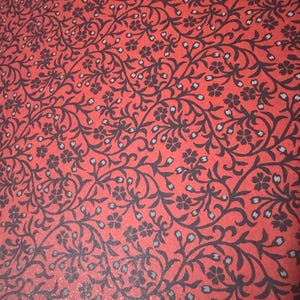 May include: Red background with a black and white floral pattern. The pattern features intricate vines and small flowers.