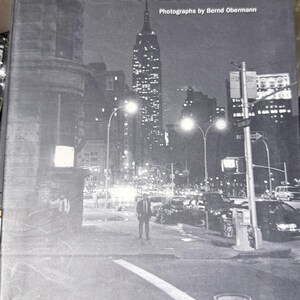 May include: A black and white photograph of New York City at night, featuring the Empire State Building. The book cover reads "NEW YORK" and "Photographs by Bernd Obermann". The publisher's logo "teNeues" is visible at the bottom.