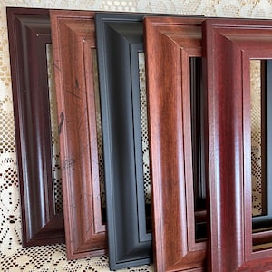 May include: Five picture frames in different colors and styles. The frames are made of wood and have a simple, classic design. The frames are arranged in a row, with the darkest frame on the left and the lightest frame on the right.