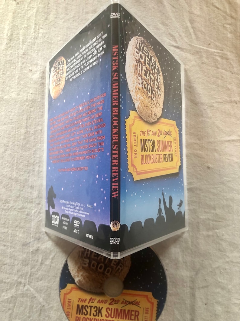 以下が含まれることがあります： 「ミステリー・サイエンス・シアター3000」の夏の話題作レビューのDVDケース。ケースは青色で、星でいっぱいの夜空の背景。前面には、「The 1st and 2nd Annual MST3K Summer Blockbuster Review」というテキストのチケットが描かれています。