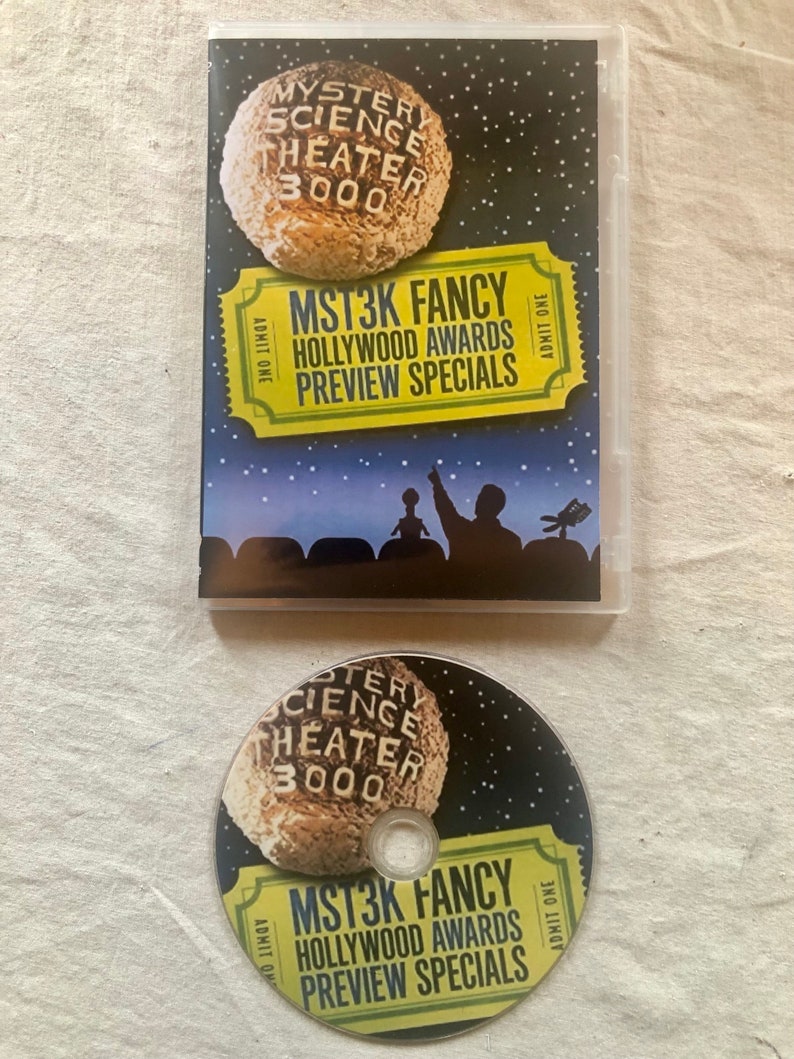 K&ouml;nnte beinhalten: Ein DVD-Geh&auml;use und eine Disc f&uuml;r die Mystery Science Theater 3000-Ver&ouml;ffentlichung "MST3K Fancy: Hollywood Awards Preview Specials". Das Geh&auml;use hat einen schwarzen Hintergrund mit einem gelben Ticket und einem Comic-Mond. Die Disc hat ein &auml;hnliches Design.