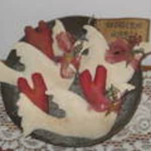 Könnte beinhalten: Keramik-Wandbehang mit einer dunkelgrauen, kreisförmigen Basis, die drei stilisierte Koi-Karpfen in Creme und Rot zeigt. Die Fische sind kreisförmig angeordnet, mit einem kleinen, rechteckigen Schild daran. Das Schild hat Text.