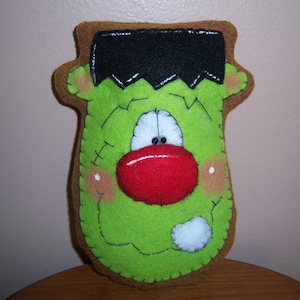 May include: Green felt Frankenstein monster with a black felt hair, red felt nose, and white felt eyes.