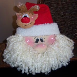 May include: A handmade Santa Claus ornament with a white beard and a red hat. A small reindeer with a red nose is perched on top of the hat.