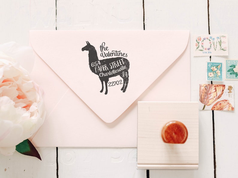 May include: A pink envelope with a black rubber stamp of a llama with the text "the Valentines 654 Paper Street Charlottesville VA 22702" inside the llama silhouette.