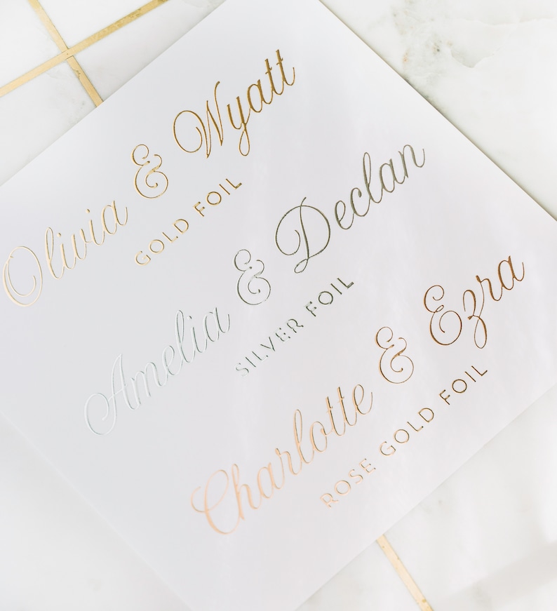 May include: White paper with gold, silver, and rose gold foil lettering. Names include Olivia & Wyatt, Amelia & Declan, and Charlotte & Ezra. The words "GOLD FOIL", "SILVER FOIL", and "ROSE GOLD FOIL" are also printed on the paper.