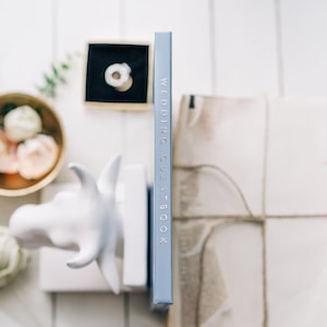 May include: A light blue book with the text "Wedding Guest Book" printed in silver on the spine.