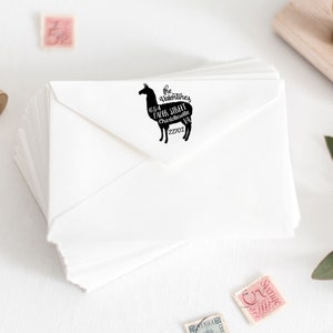 May include: A black and white rubber stamp featuring a llama silhouette with the text "The Valentines 654  Faircloth Street Charlottesville VA 22702" printed inside the llama.