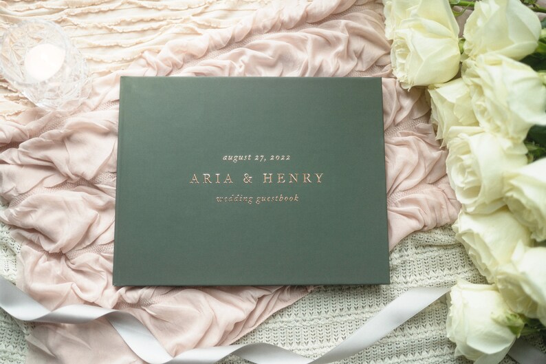 Może przedstawiać: Zielony, ślubny notes dla gości z napisem "August 27, 2023 Aria & Henry wedding guestbook" w złotych literach.