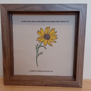 May include: A framed print with a yellow sunflower illustration and the text "Saying she likes sunflowers describes her perfectly. Always looking for the sun."
