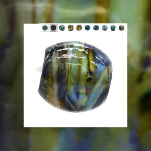 May include: A close-up of a blue, green, and gold iridescent glass bead. The bead has a swirling pattern and is smooth and shiny.
