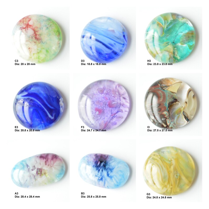 May include: Nine round and oval glass cabochons with various colorful patterns and swirls. The cabochons are approximately 20 to 28 millimeters in diameter.
