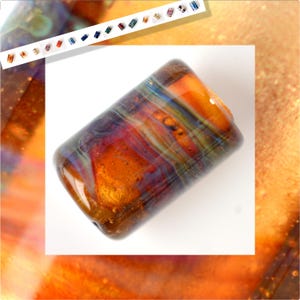 Puede incluir: Una cuenta de vidrio rectangular hecha a mano. La cuenta presenta una mezcla de colores cálidos, incluyendo naranja, marrón y toques de azul y verde. El vidrio tiene un efecto arremolinado y veteado, creando una apariencia única y artística.