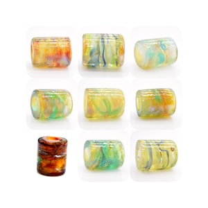 Puede incluir: Nueve cuentas de vidrio con una variedad de remolinos y patrones coloridos. Las cuentas son de forma cilíndrica y tienen una apariencia translúcida.