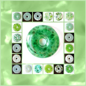 Könnte beinhalten: Eine Sammlung von 20 grünen und weißen Donut-förmigen Anhängern mit einem Loch in der Mitte. Die Anhänger sind aus Glas und haben eine gesprenkelte Optik.