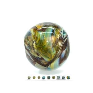 Puede incluir: Una canica de vidrio redonda, verde, marrón y azul con patrones de remolino.