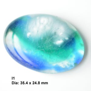 May include: A large, oval-shaped, blue, green, and white glass paperweight with a swirling pattern. The paperweight measures 35.4 x 24.8 mm.