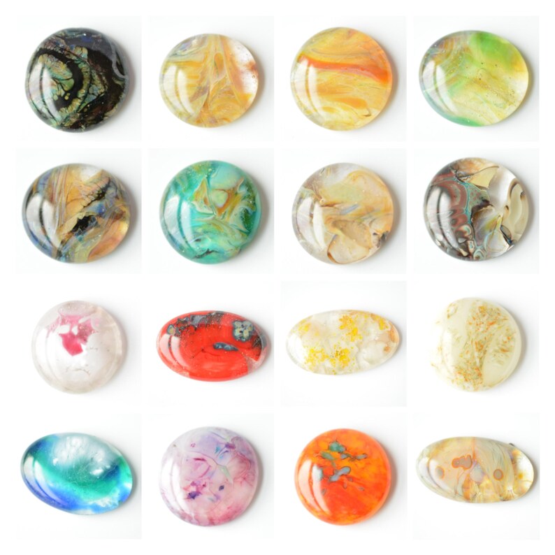 May include: Assortment of 12 round and oval-shaped resin cabochons with various abstract patterns in shades of blue, green, red, yellow, and white.