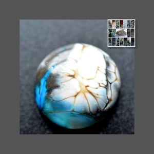 May include: A round, blue, white, and brown glass cabochon with a marbled pattern. The cabochon is smooth and shiny.