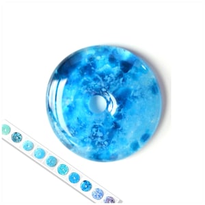 以下が含まれることがあります： 中央に穴が開いた丸い青いガラスビーズ。ビーズは、薄青と濃い青のグラデーションで、まだらで曇ったような外観をしています。