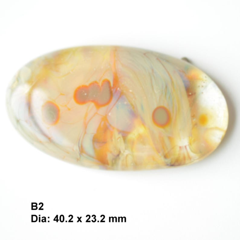 May include: A smooth, oval-shaped, translucent glass paperweight with swirling patterns of white, yellow, orange, and brown. The paperweight measures 40.2 x 23.2 mm.