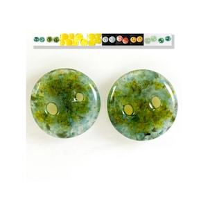 May include: Two green and blue glass buttons with a speckled pattern. The buttons have two holes each.