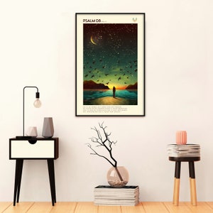 May include: A black framed poster featuring a dark blue, green, and brown illustration of a person standing on a beach looking out at a body of water. The sky is dark blue with a crescent moon and stars. The poster has the text "PSALM 08" and a verse of scripture in Dutch.