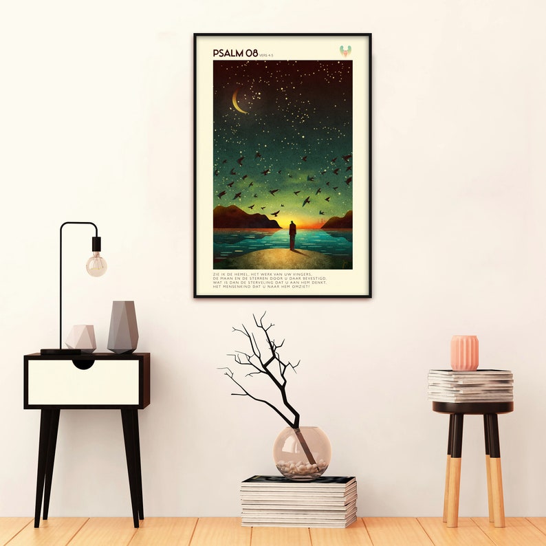 May include: A black framed poster featuring a dark blue, green, and brown illustration of a person standing on a beach looking out at a body of water. The sky is dark blue with a crescent moon and stars. The poster has the text "PSALM 08" and a verse of scripture in Dutch.