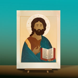May include: A painting of Jesus Christ holding a book with text in a red, white and blue colour scheme. The painting is framed in a gold frame and has a light brown background.