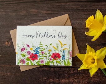 May include: A white card with a floral design and the text "Happy Mother's Day". The card is surrounded by a brown envelope and yellow daffodils.